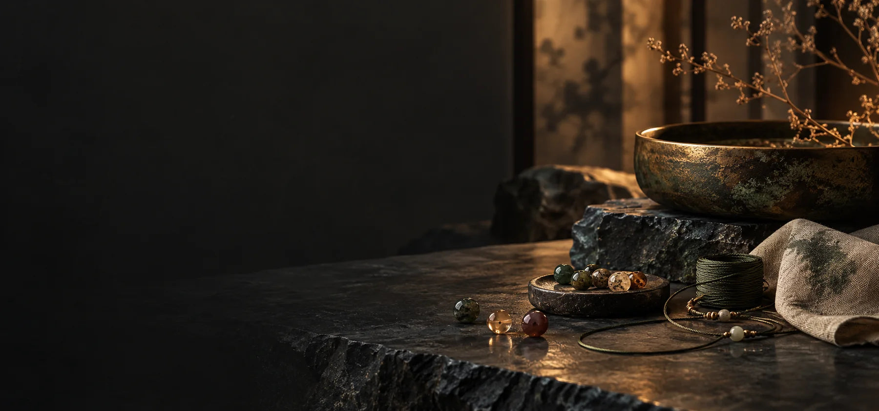 A quiet artisan table with mineral beads, silk cord and an aged bronze vessel