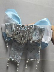 Close-up of blue brocade bow hair accessory with silver triangle bell