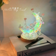 Holographic moon and butterfly night light displayed on a bedside table